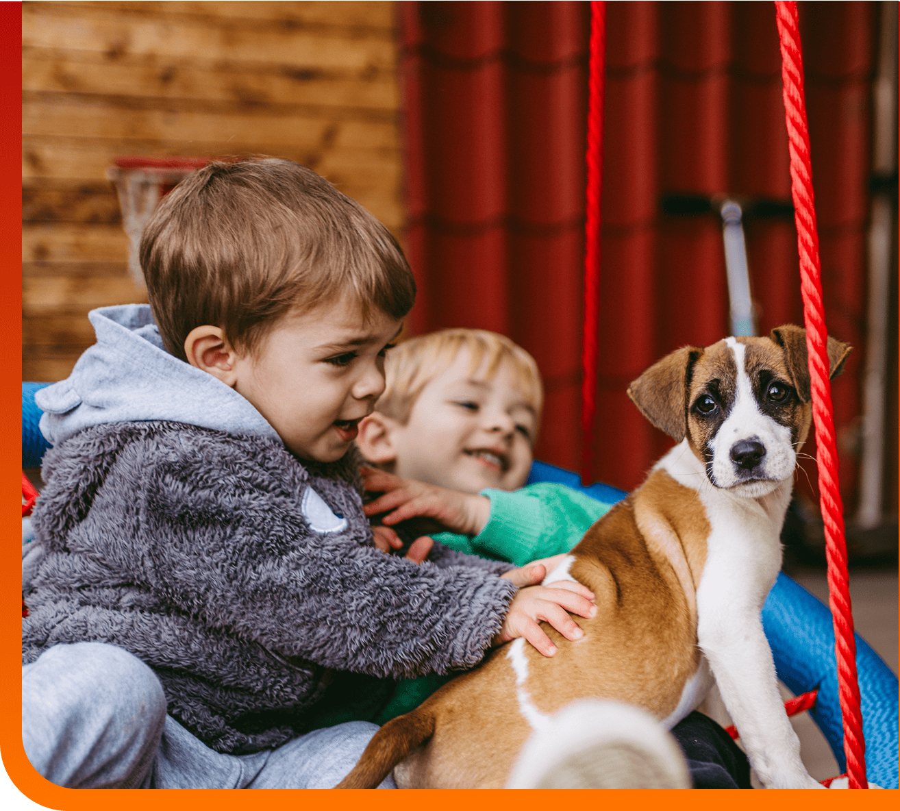 Two children playing on a swing with a puppy.