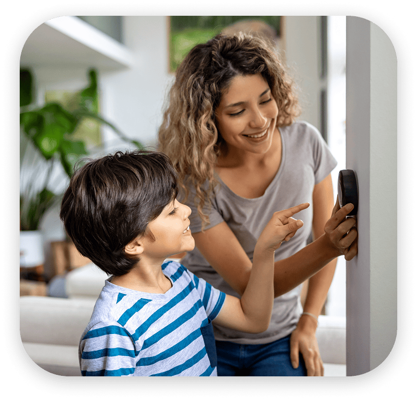 Mother showing son how to adjust the smart thermostat in their Joplin, Missouri home.
